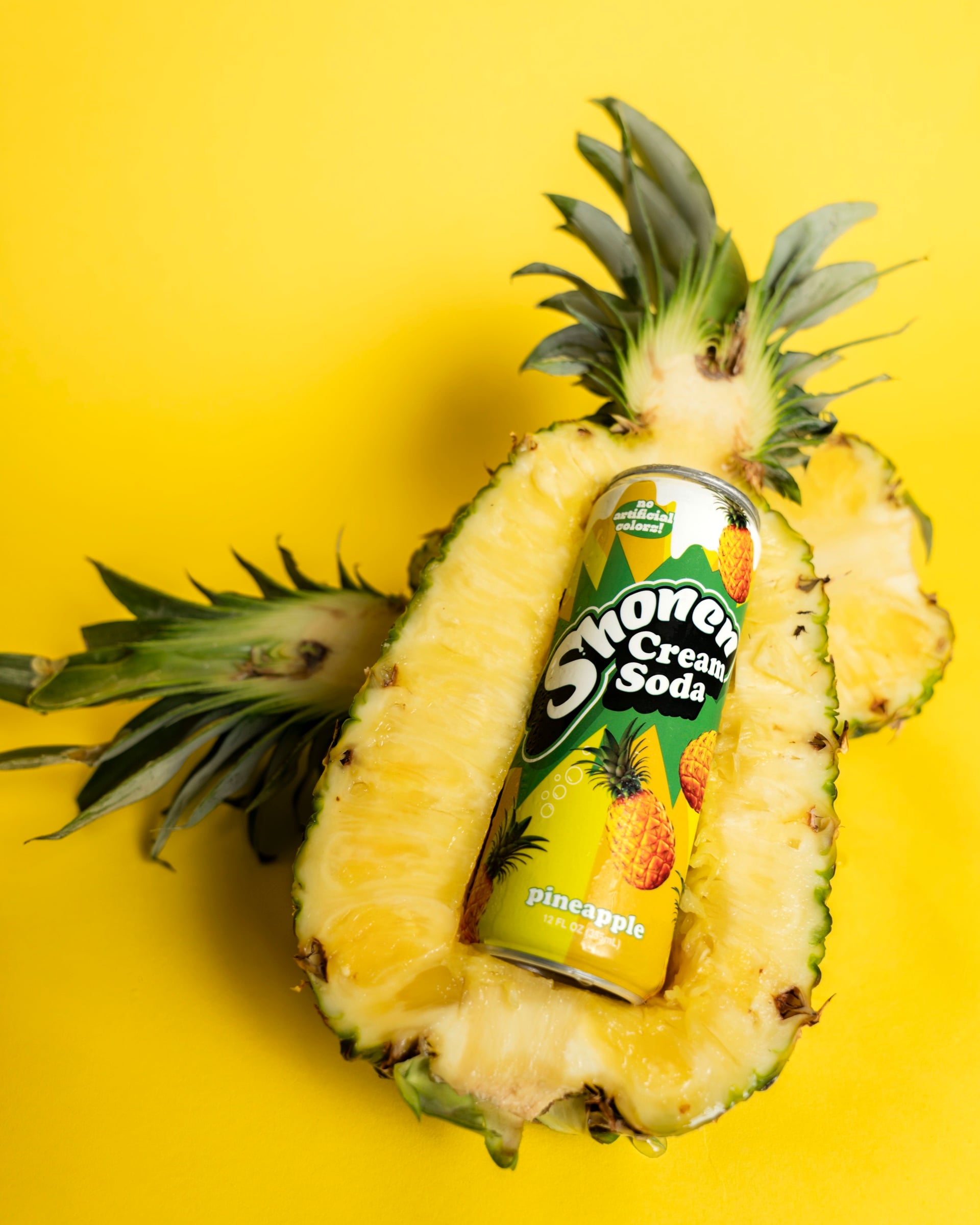 Shonen pineapple cream soda can nestled in a halved fresh pineapple on yellow