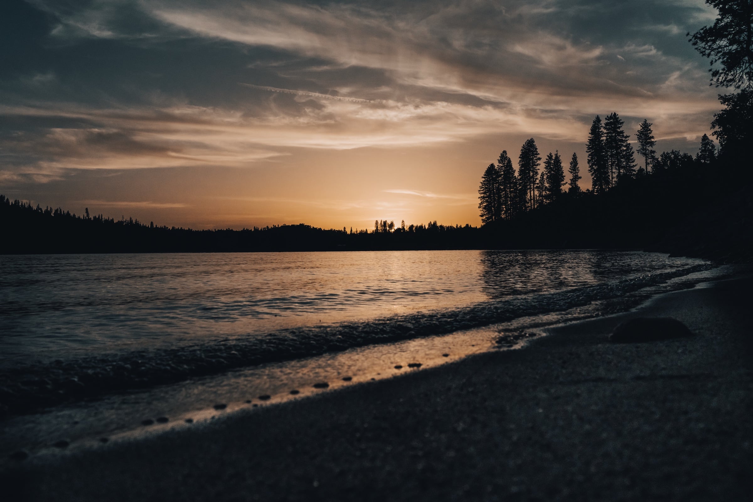 Silhouetted point of land reaching into a glowing dusk lake
