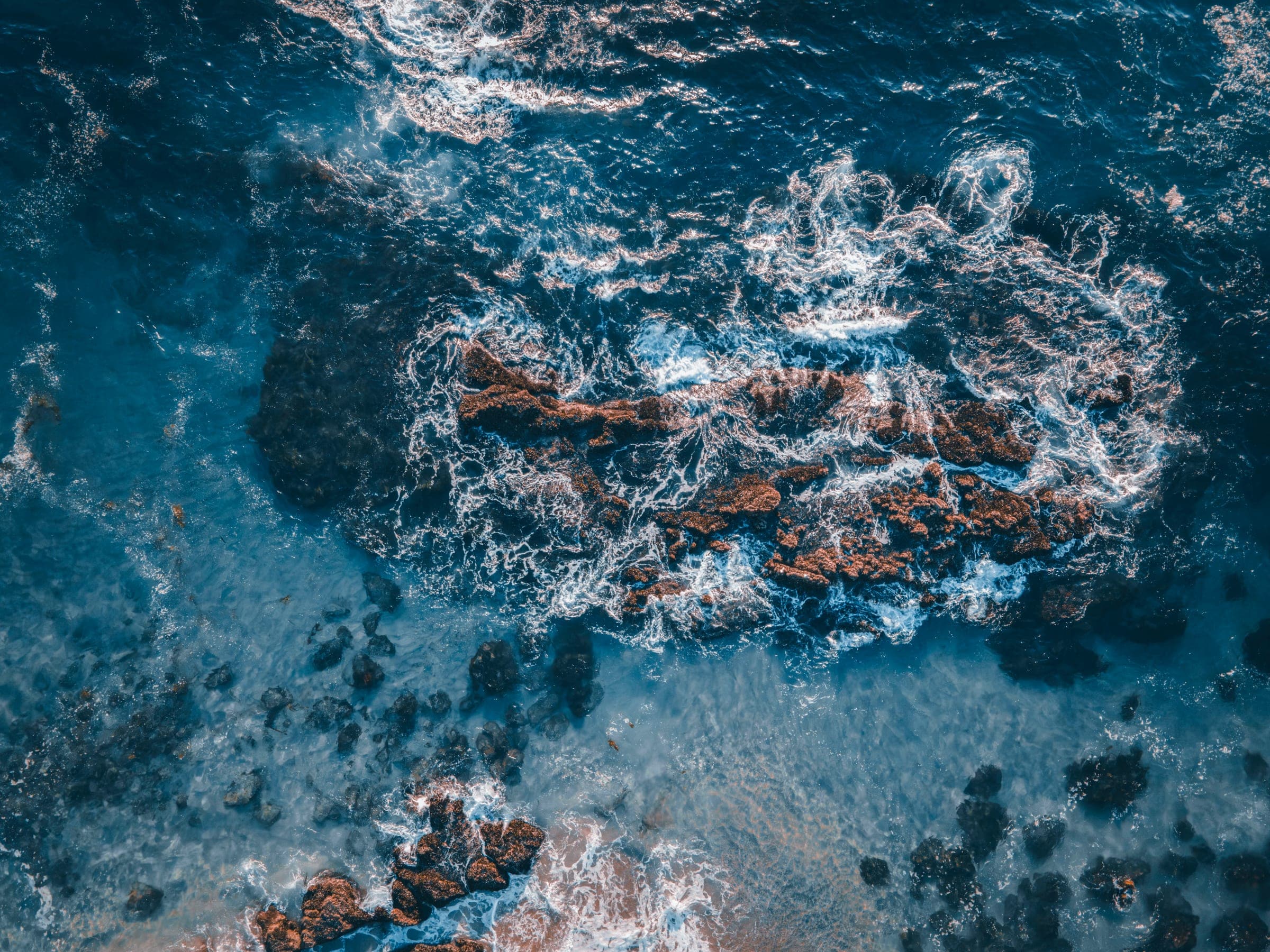 Aerial view of waves breaking around a submerged rocky reef