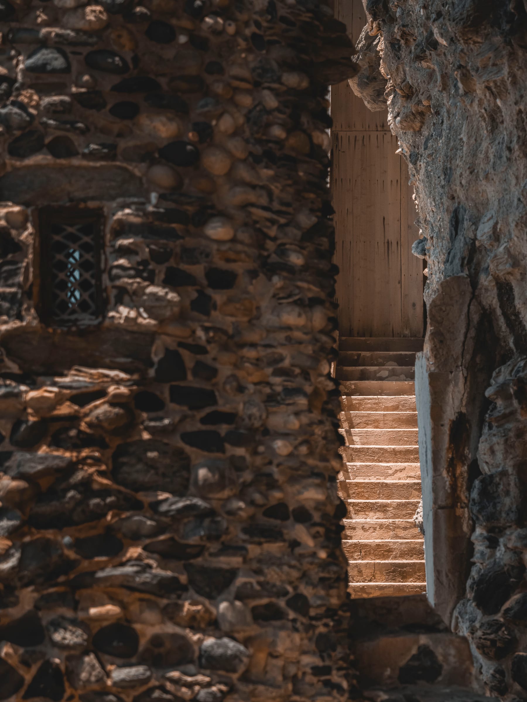 Sunlit stone steps rising between rough cobblestone walls at the coast