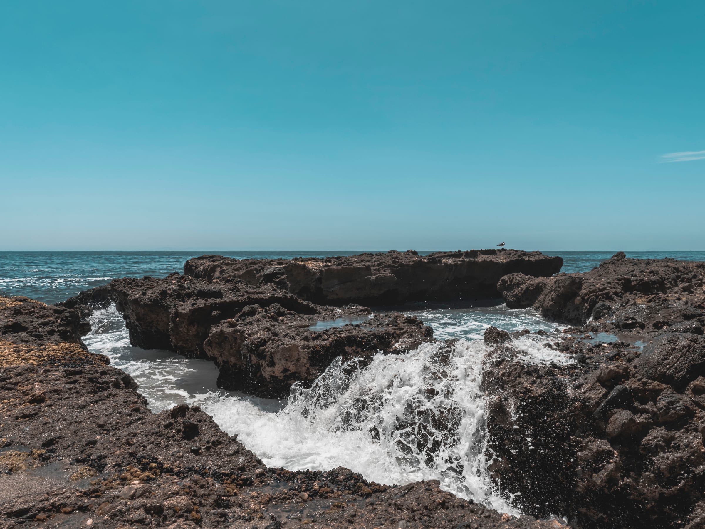 Low waves washing over a flat rock shelf toward the open sea
