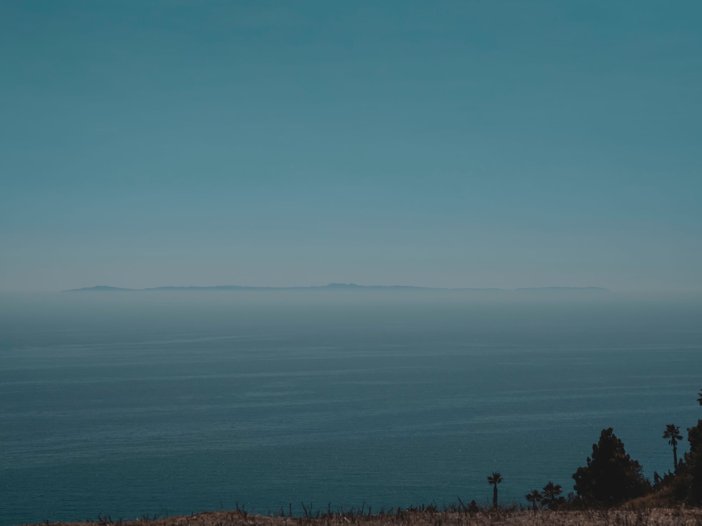 A distant island fading into haze across a calm silver sea