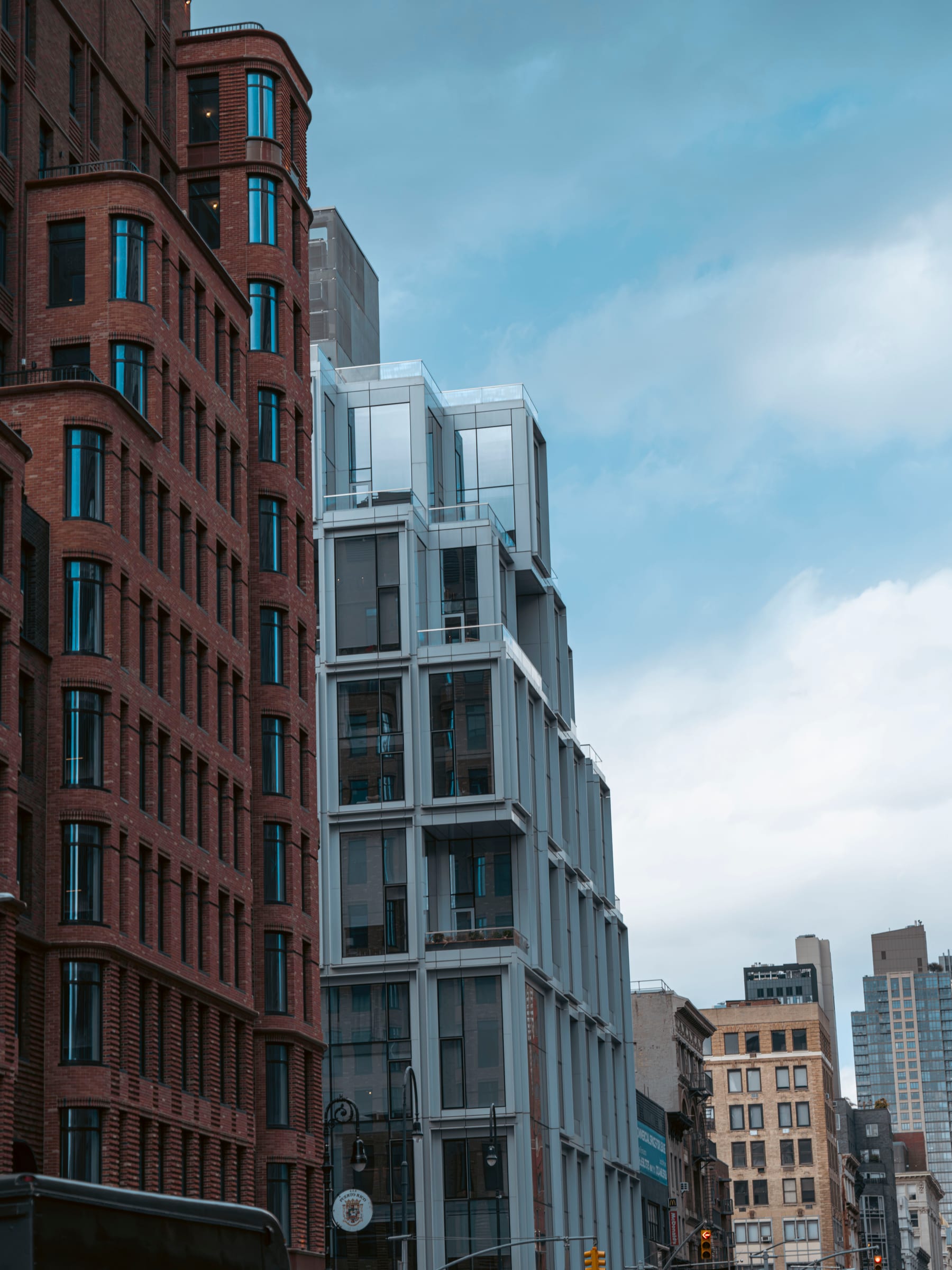 A slender modern glass tower wedged beside old brick buildings