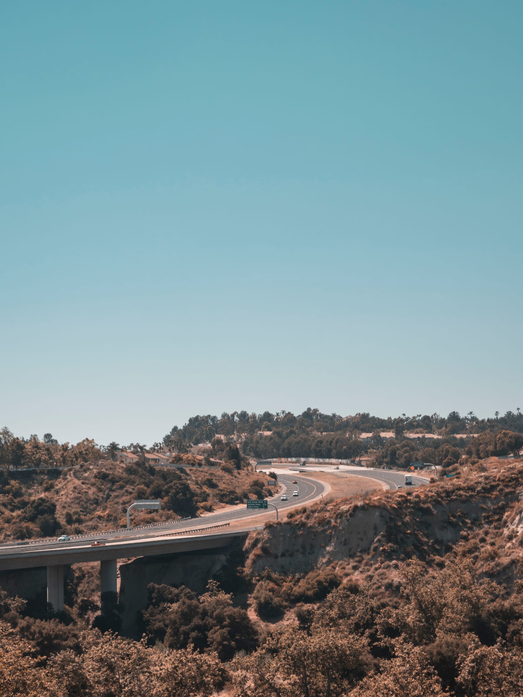 A highway bridge curving through dry rolling hills under a clear sky