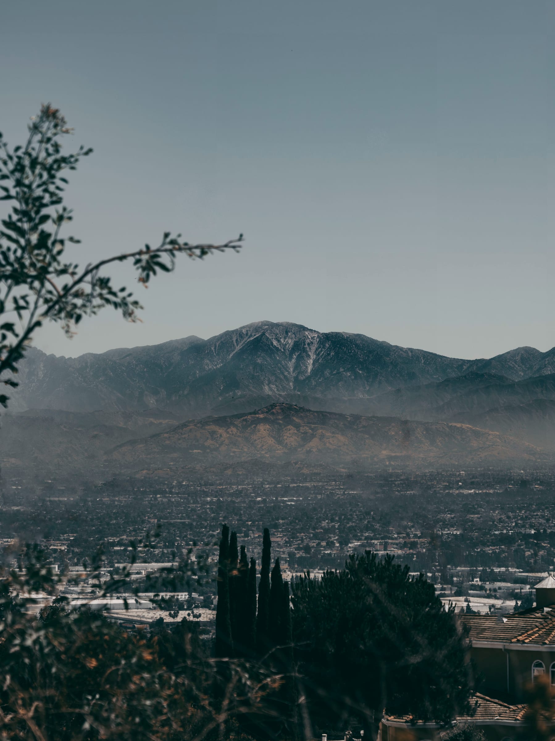 Snow-dusted peaks rising beyond a hazy valley at golden hour