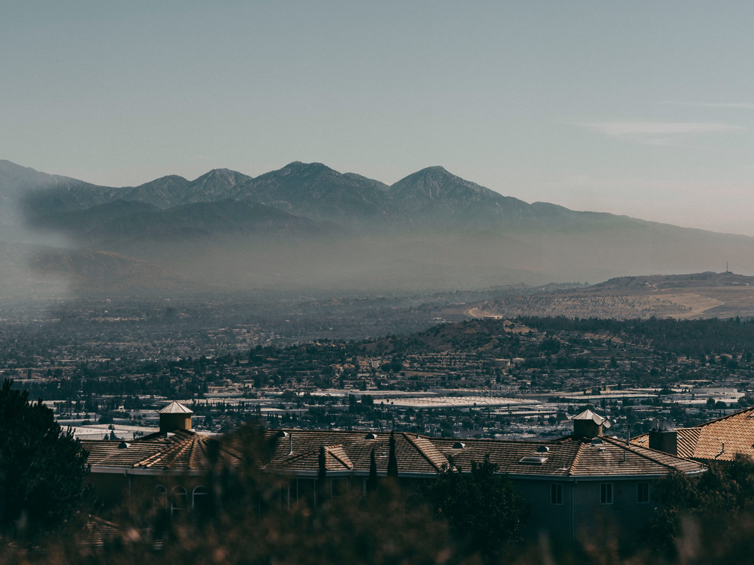 Layered mountain range fading into haze above distant rooftops