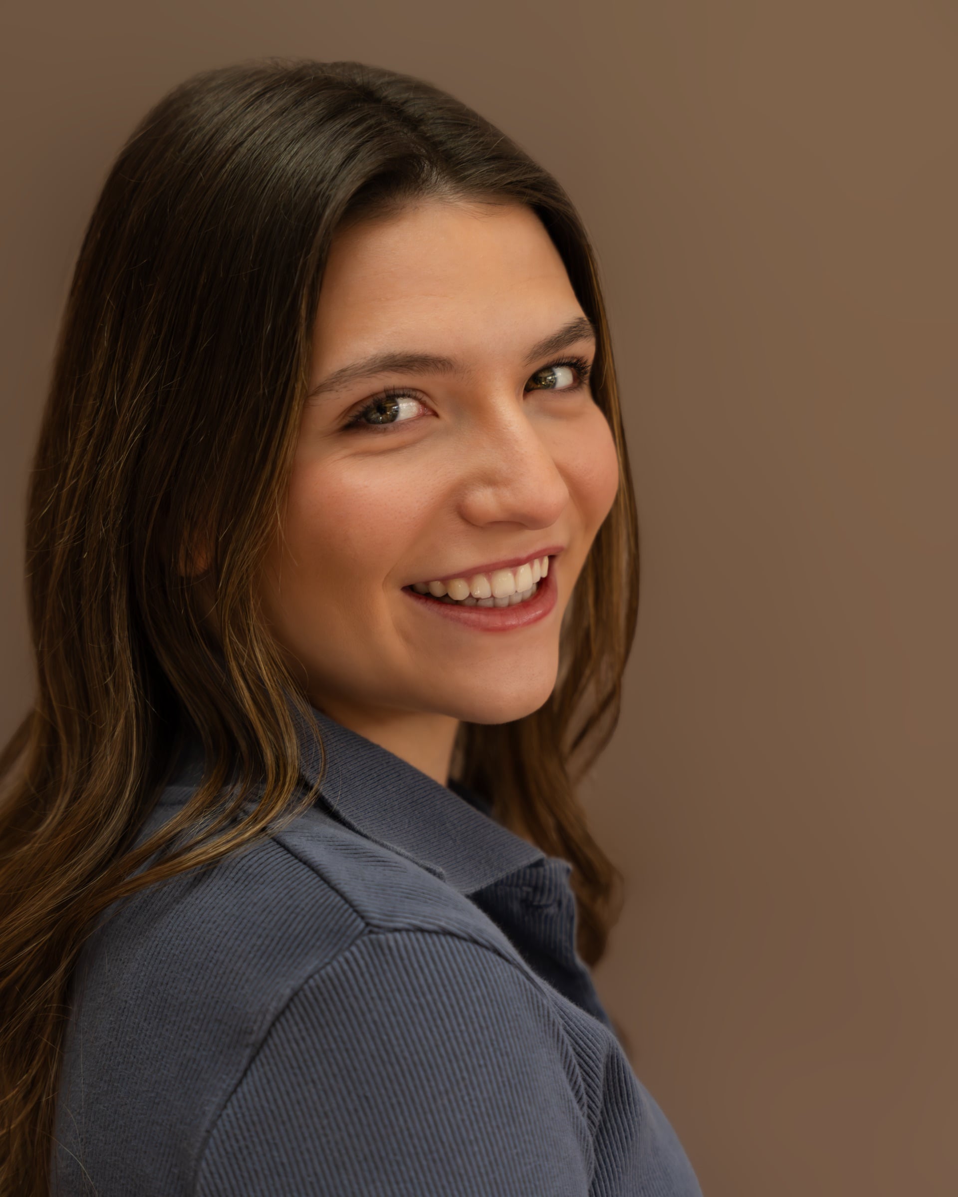 Studio headshot of a woman in a blue top laughing and looking off-camera