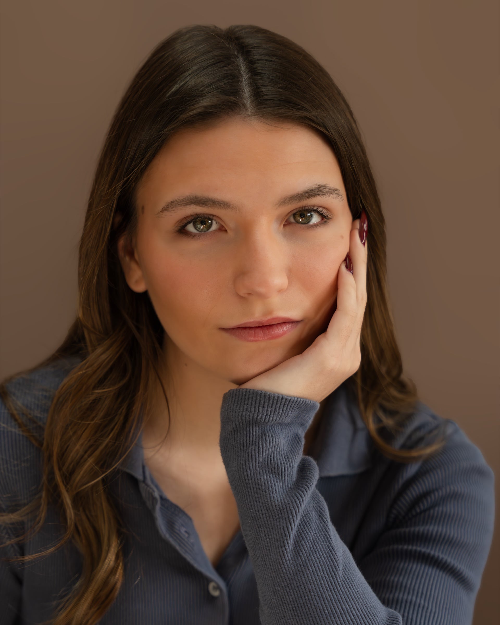 Studio headshot of a woman in a blue top with a calm, direct gaze