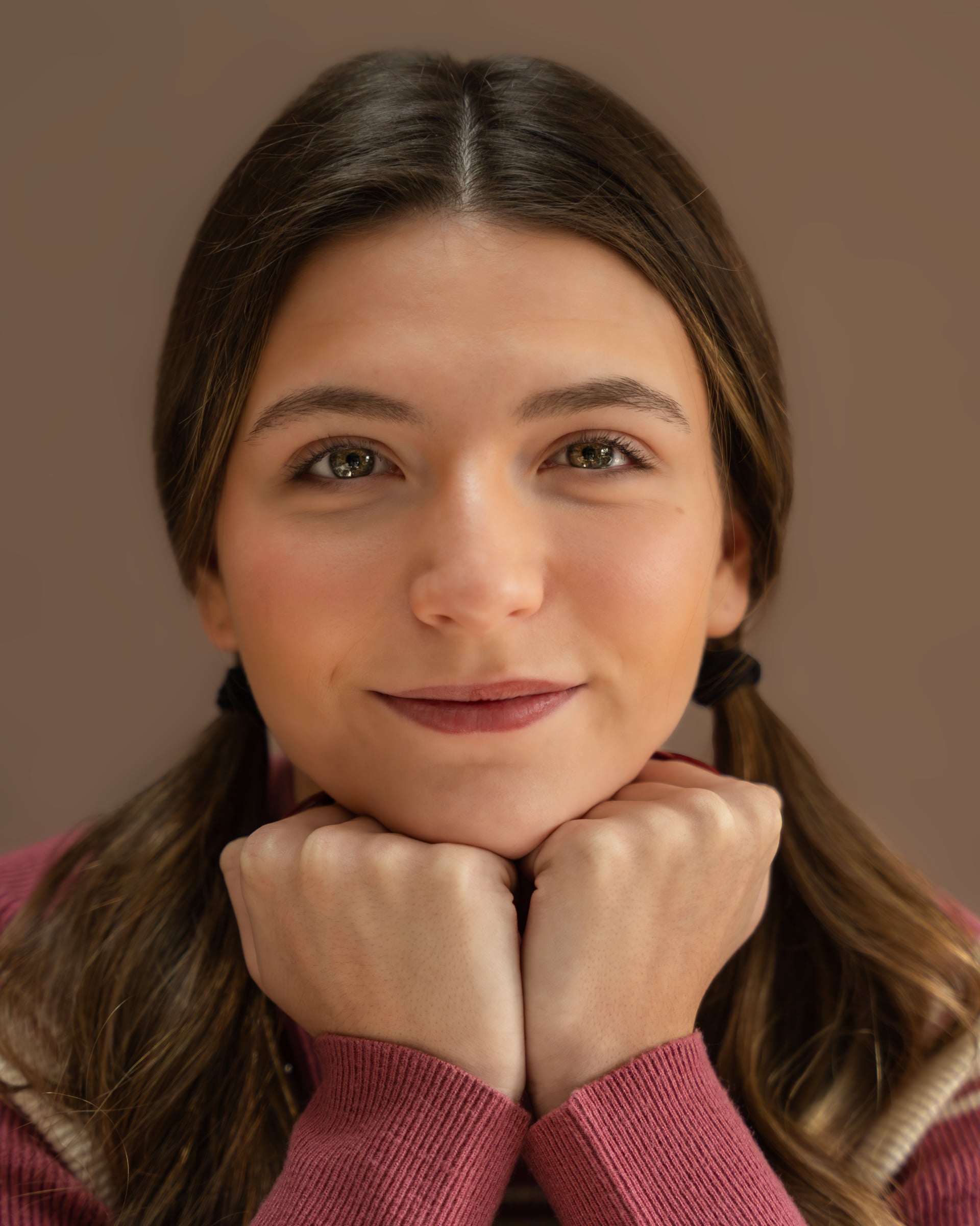 Studio headshot of a woman in a rose top smiling softly at the camera